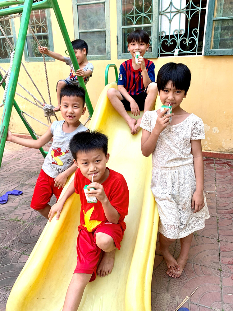 Em Lan Thương (áo đầm trắng) cùng các bạn quây quần uống sữa bên chiếc xích đu trong trung tâm